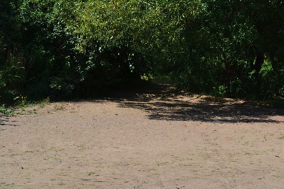 Sand/dirt surface on the bank of the river where both the hard and natural surface trails lead to the river